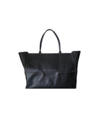 Métier black leather tote bag with dual top handles, structured silhouette and subtle logo detailing.