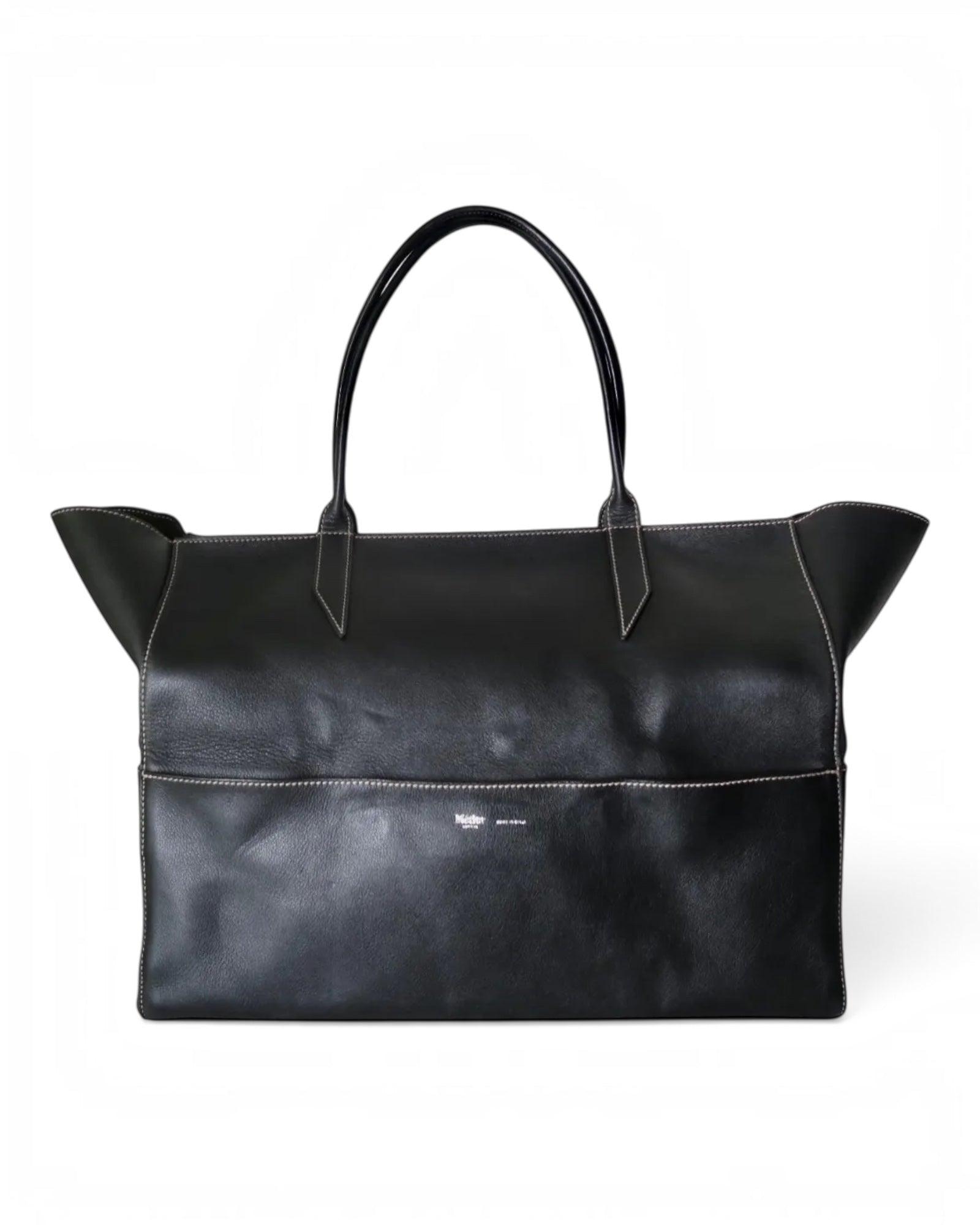 Métier black leather tote bag with dual top handles, structured silhouette and subtle logo detailing.