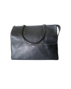 Métier black leather tote bag with dual top handles, structured silhouette and subtle logo detailing.