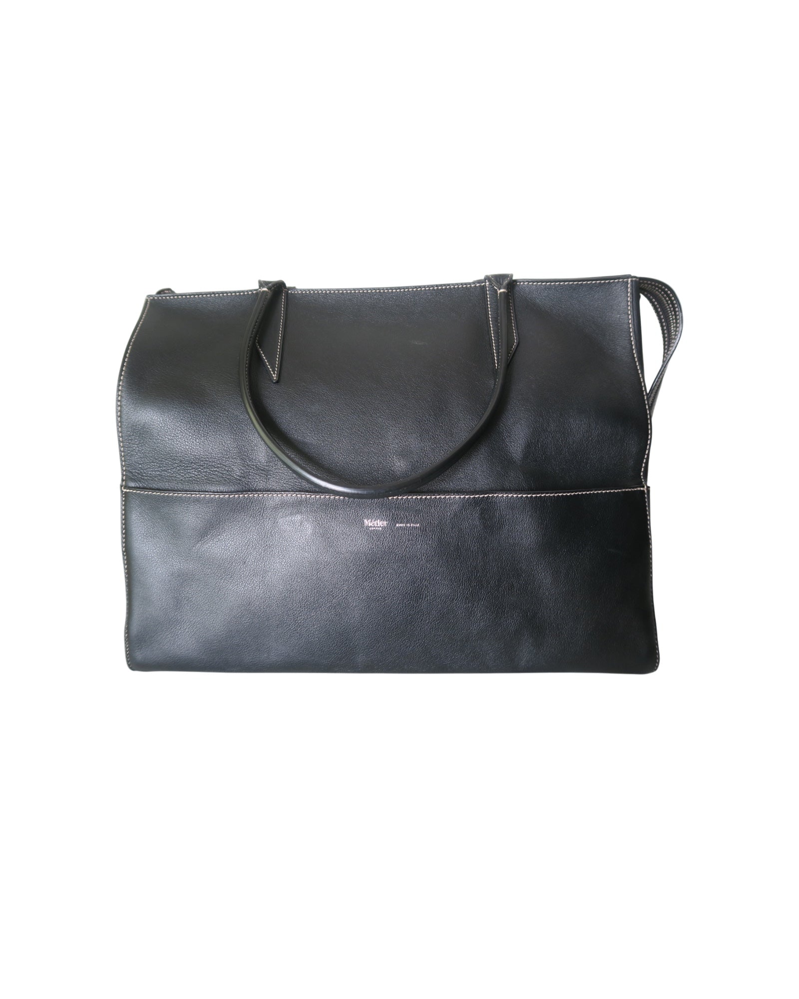 Métier black leather tote bag with dual top handles, structured silhouette and subtle logo detailing.